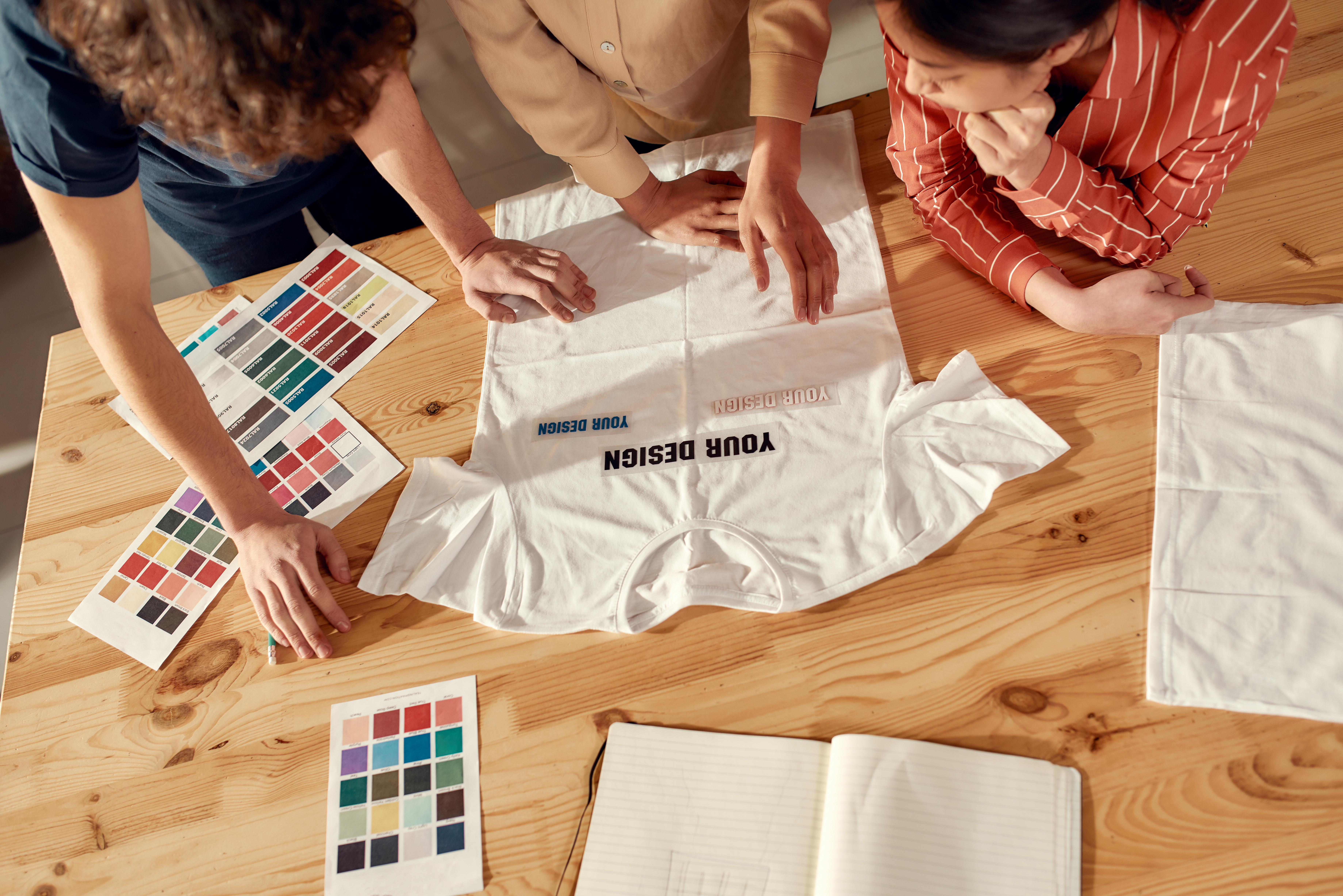three people looking at color choices for a branded t-shirt design
