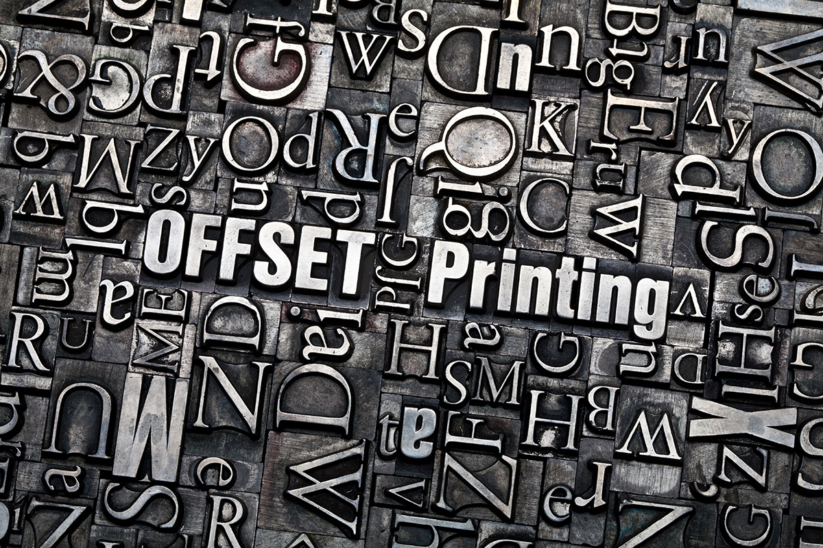 Various metal plates of different letters scattered together with the words “Offset Printing” in the center.