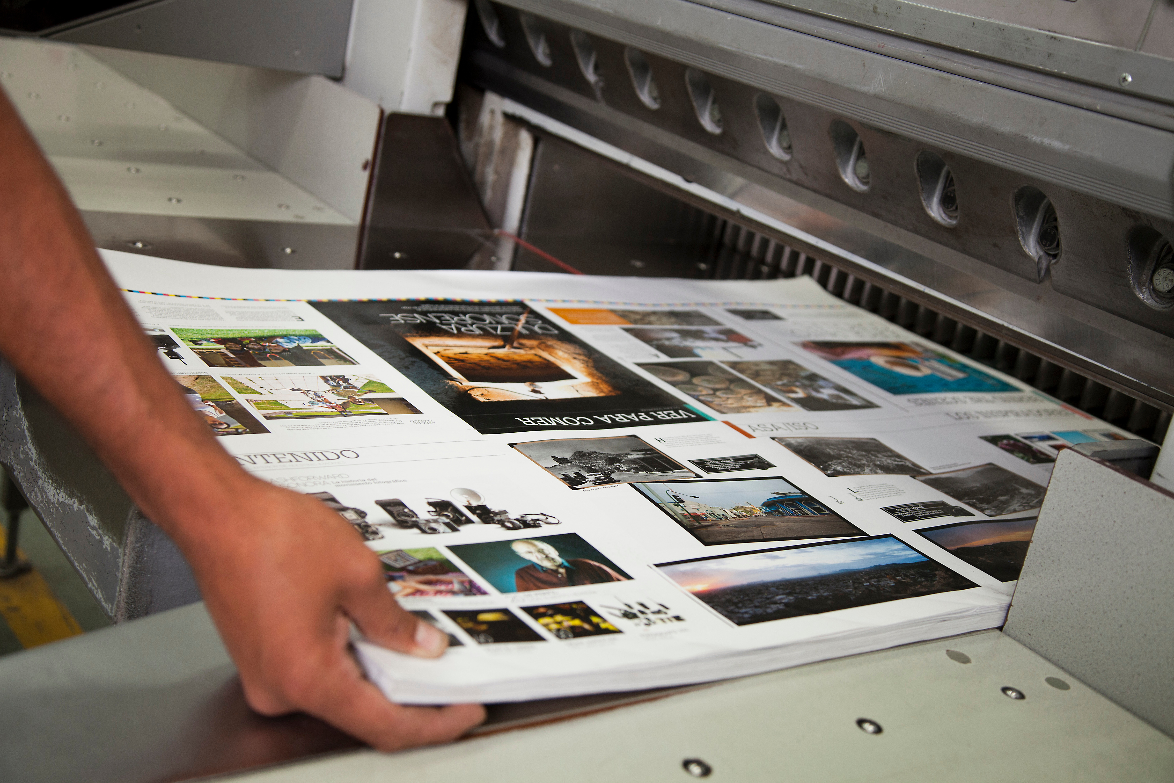 A person takes a stack of printed catalogs off a printer.