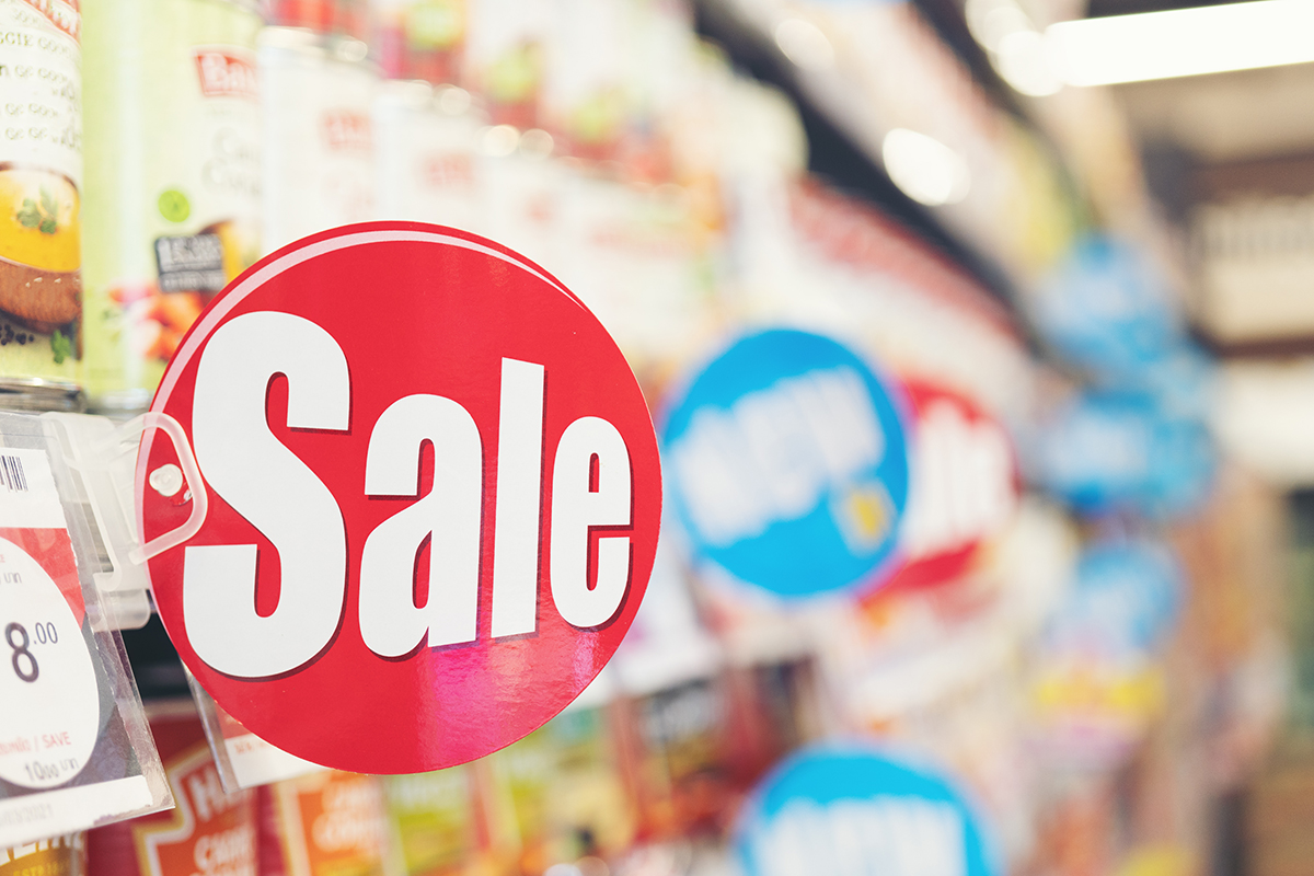 An image of a bold, round, red sign on a store shelf with white text that says “sale.”